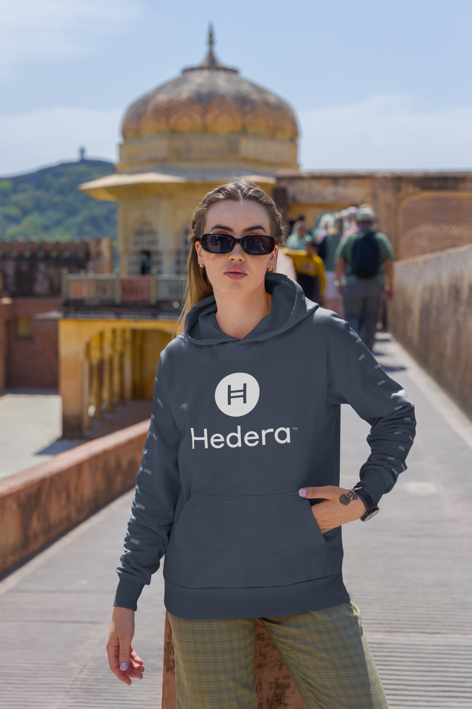 Person wearing a Hedera hoodie in front of an architectural structure with domes.