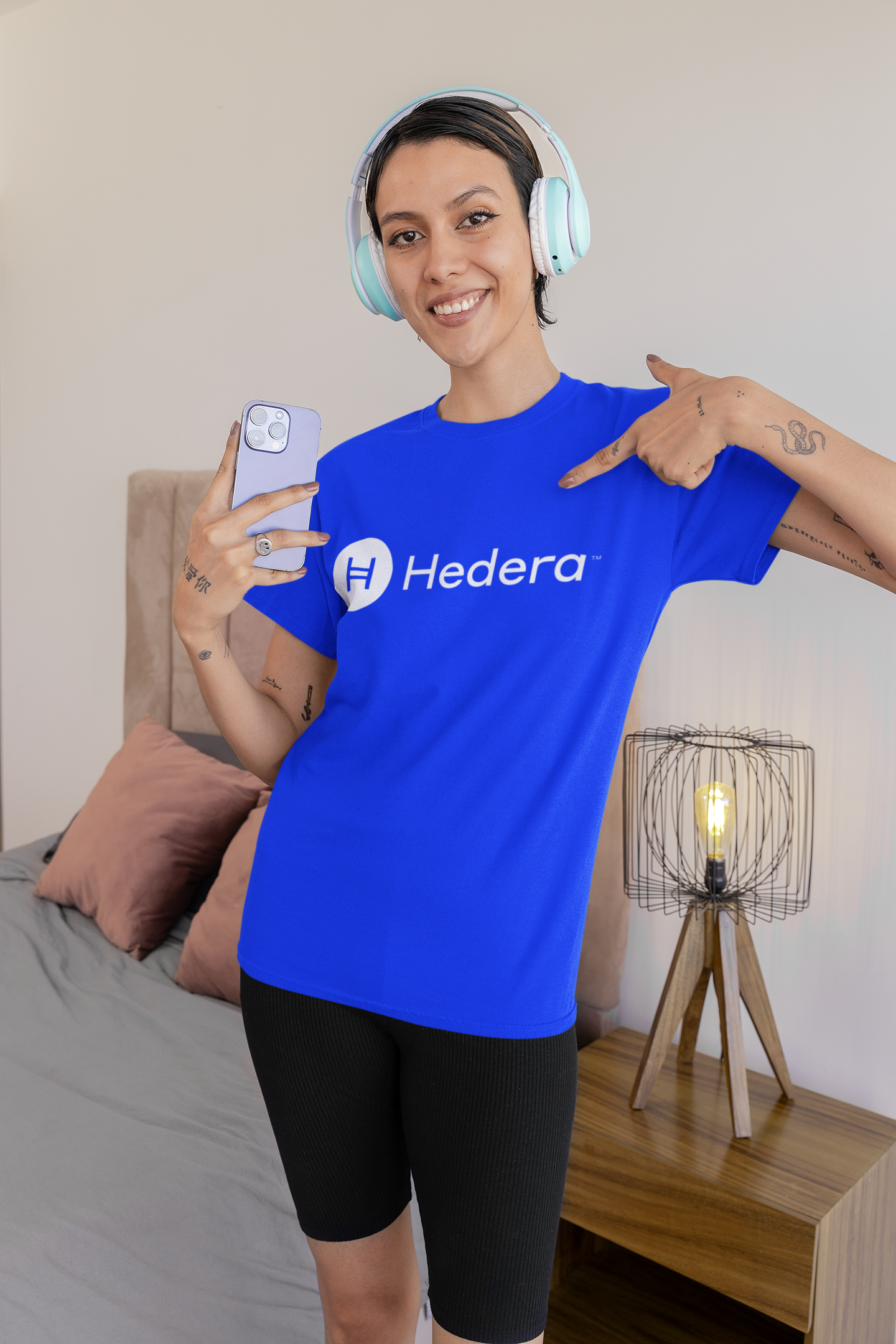Person wearing a blue Hedera t-shirt in a bedroom setting