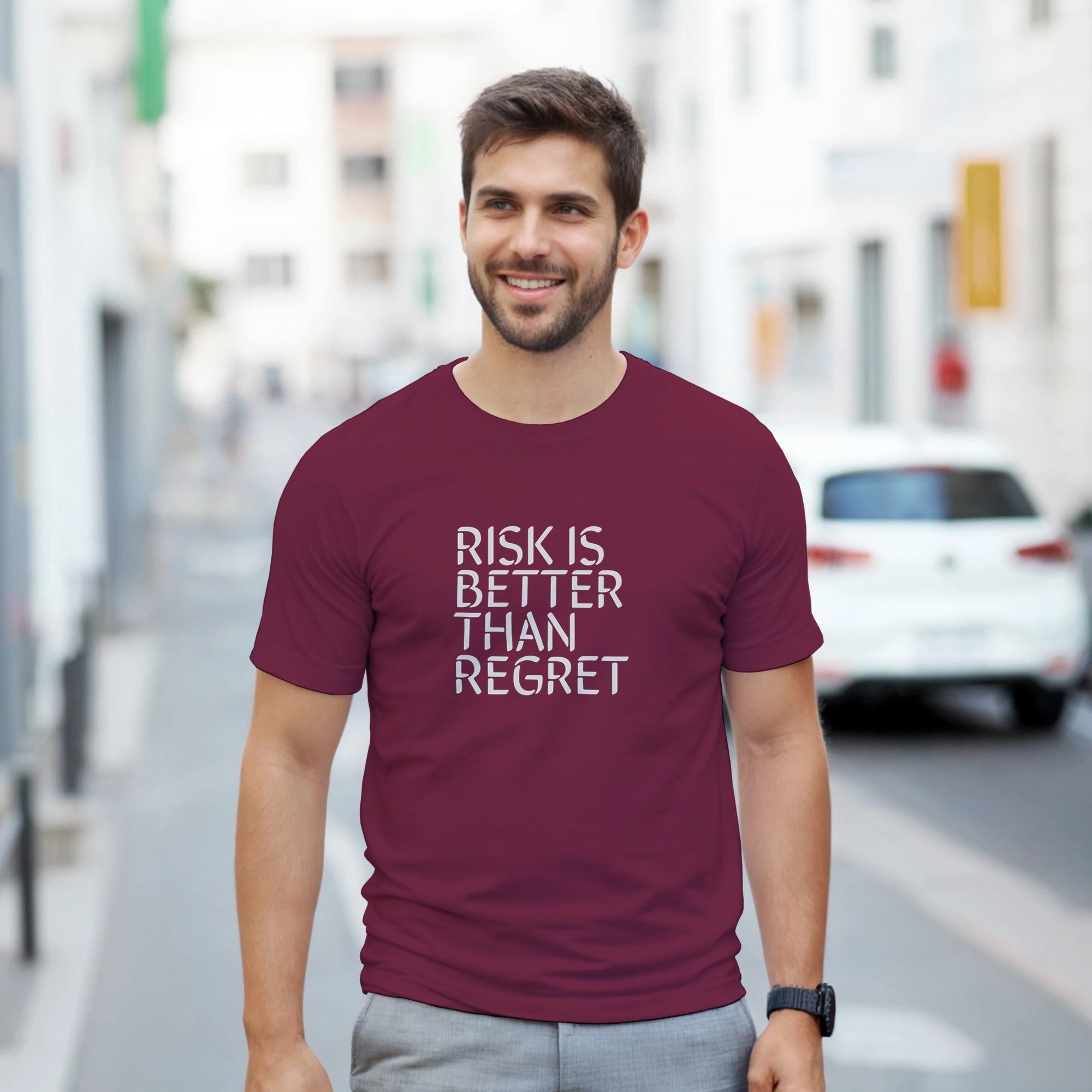 Man wearing a maroon t-shirt with 'RISK IS BETTER THAN REGRET' text on a city street.