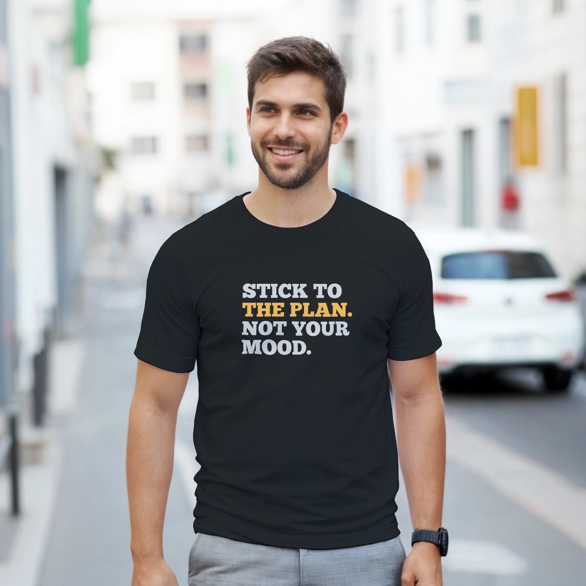 Man wearing a black t-shirt with motivational quote on a city street