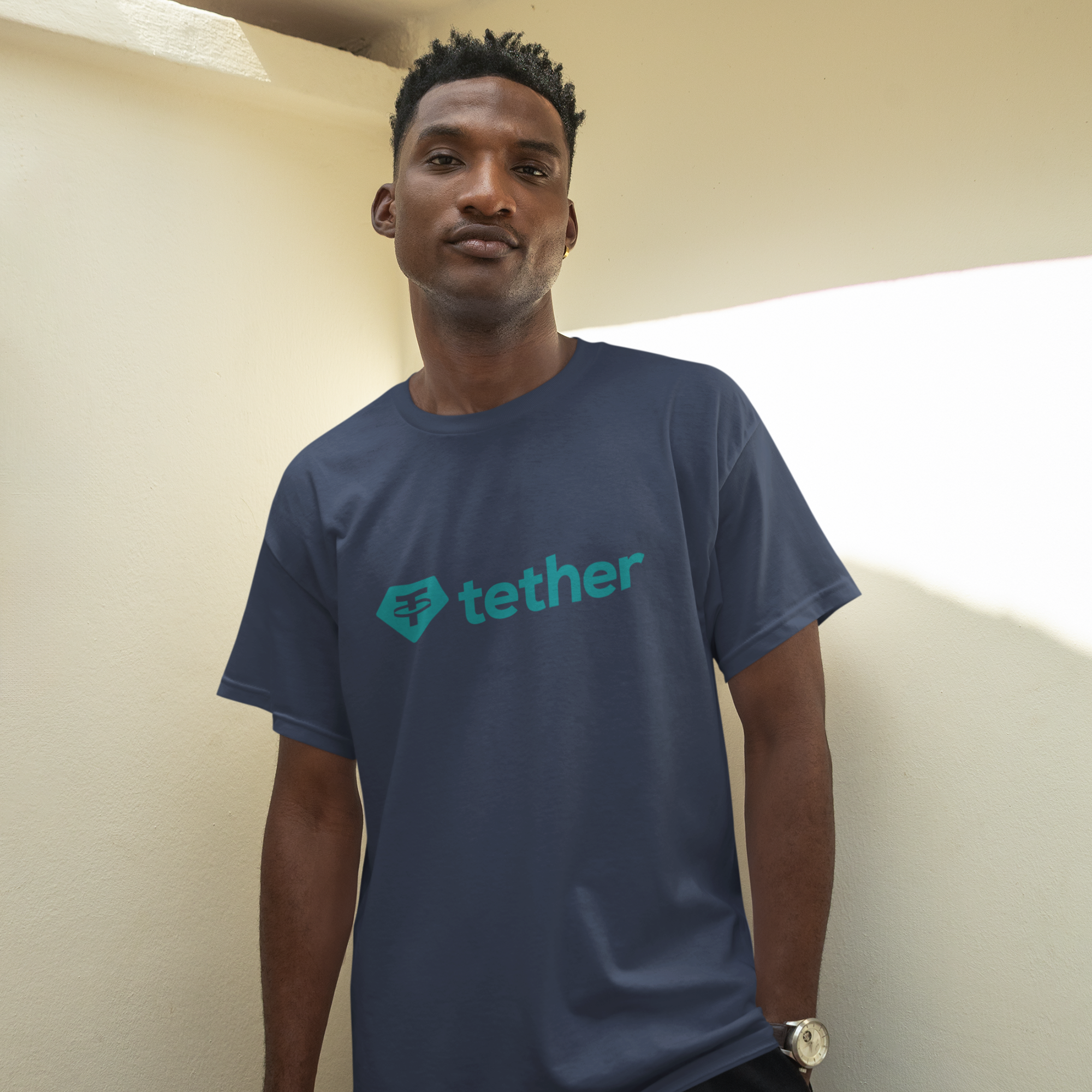 Person wearing a blue T-shirt with 'tether' logo against a plain wall