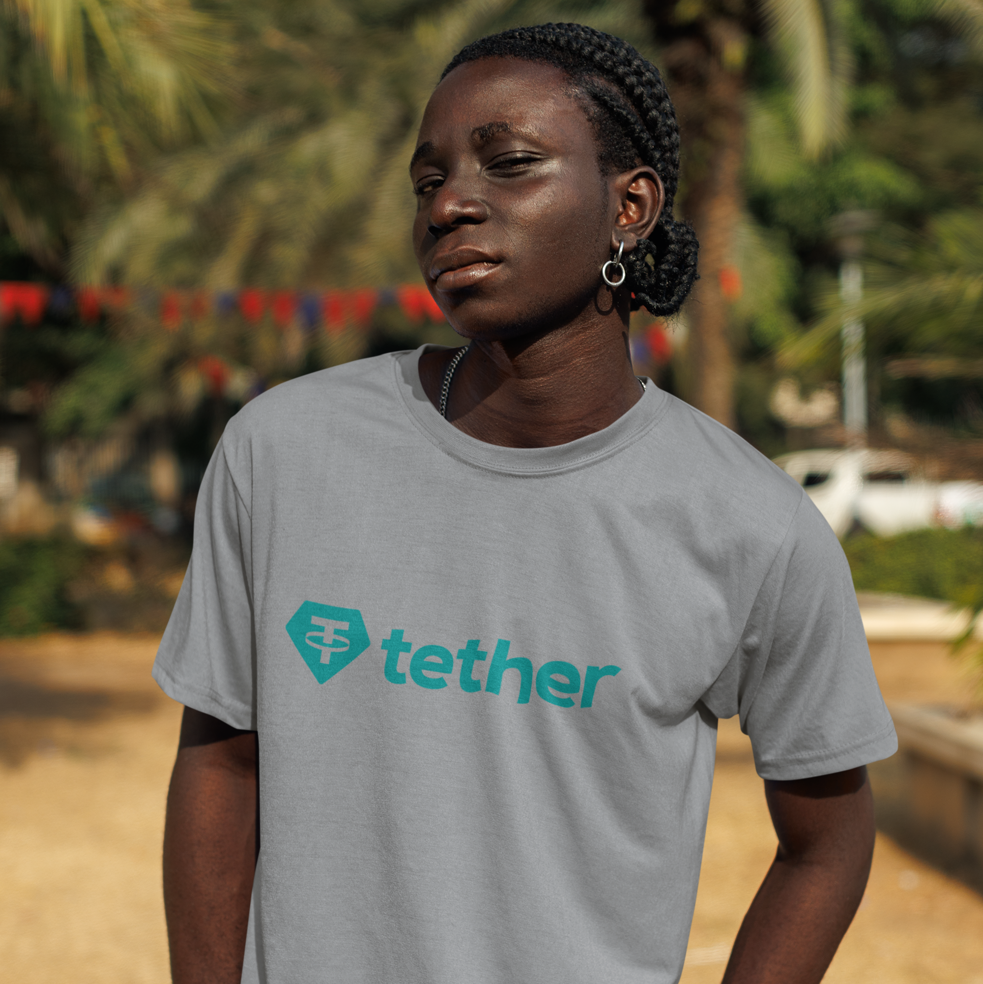 Person wearing a gray T-shirt with Tether logo outdoors